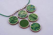 Green statement necklace made with fabric on light wood base