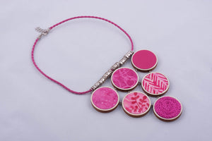 Pink statement necklace made with fabric on light wood base