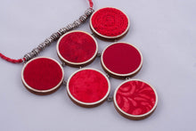 Red statement necklace made with fabric on light wood base