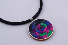 Statement necklace made with colorful yarn on light wood base