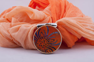 Orange scarf with pendant made with fabric on light wood base (shades of orange)
