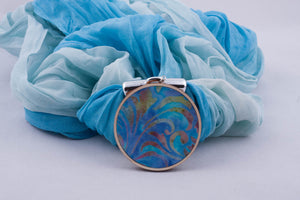 Light blue scarf with pendant made with fabric on light wood base (shades of light blue)